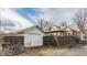 Exterior view of the home and detached garage, featuring a gravel driveway and fenced-in yard at 6189 Primrose Ave, Indianapolis, IN 46220