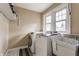 Bright laundry room features a utility sink, white washer and dryer, and a window overlooking the backyard at 6189 Primrose Ave, Indianapolis, IN 46220