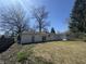 A backyard showcasing the house's exterior, complemented by mature trees and dormant grass at 7406 E 33Rd St, Indianapolis, IN 46226