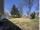 A view of the backyard featuring a perimeter fence and mature trees with dormant grass at 7406 E 33Rd St, Indianapolis, IN 46226