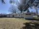 A spacious backyard view with a glimpse of the house's back exterior featuring windows and sliding glass doors at 7406 E 33Rd St, Indianapolis, IN 46226