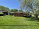 Lovely backyard featuring lush green grass, mature trees, and the brick house with a round window at 2130 Theobald St, Shelbyville, IN 46176