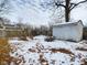 Snowy backyard featuring bare trees, fallen leaves, and a small shed at 2613 E 7Th St, Anderson, IN 46012