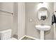 This powder room features a pedestal sink, a round mirror, and modern fixtures at 2792 Maricopa Blvd, Whitestown, IN 46075