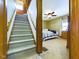 Hallway view of carpeted stairs leading to the upper level and bedroom with ceiling fan at 3016 Sheridan St, Anderson, IN 46016