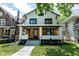 Charming two-story home with front porch featuring wood and white painted brick accents and manicured landscaping at 633 E 32Nd St, Indianapolis, IN 46205