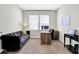 Bright home office with a dark sofa, wooden desk, and natural lighting from the window at 8148 Ebaugh Dr, Camby, IN 46113