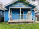Charming blue one-story home featuring a covered front porch, complemented by a small front yard at 945 N Ewing St, Indianapolis, IN 46201