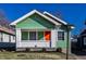 Charming green home with a bright orange front door and white brick porch at 1130 E Bradbury Ave, Indianapolis, IN 46203