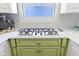 Close-up of a kitchen stove with a marble countertop and green cabinets at 11338 Bayhill Way, Indianapolis, IN 46236