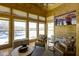 Bright sunroom featuring wood-paneled walls, a ceiling fan, and views of the frozen lake at 11338 Bayhill Way, Indianapolis, IN 46236