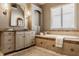 Bright bathroom showcasing a large soaking tub, tiled surround, granite countertops, and custom vanity at 11573 Bent Tree Ct, Zionsville, IN 46077