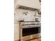 Gourmet kitchen featuring a stainless steel oven, range hood, and marble backsplash at 11573 Bent Tree Ct, Zionsville, IN 46077