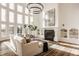 Sunlit living room boasts soaring windows, a modern chandelier, and cozy fireplace at 11573 Bent Tree Ct, Zionsville, IN 46077