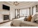Bright main bedroom with a fireplace, tray ceilings, and large windows with views at 11573 Bent Tree Ct, Zionsville, IN 46077