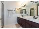 Bathroom vanity featuring dual sinks, dark cabinets, and a large, well-lit mirror at 12107 Castle Row Overlook, Carmel, IN 46033