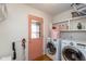 Functional laundry room with white washer and dryer, peach door and shelving for storage at 12107 Castle Row Overlook, Carmel, IN 46033