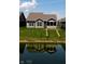 Back of a home with a backyard pond, light gray siding, and large windows for natural light at 1223 Blackthorne S Trl, Plainfield, IN 46168