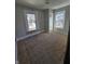 Bedroom featuring plywood subfloor, neutral walls, with two windows and a closet at 123 S Butler Ave, Indianapolis, IN 46219