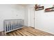 Bedroom with wood-look floors, a gray crib, and small decorative shelves at 12329 Wolf Run Rd, Noblesville, IN 46060