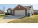 View of the two-car garage with a concrete driveway, partial brick, and vinyl siding at 12329 Wolf Run Rd, Noblesville, IN 46060