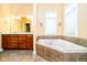 Bright bathroom showcasing a soaking tub with tile surround, double sink vanity, and a large window at 14020 Quarter Horse Ct, Carmel, IN 46032