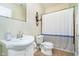 Bright bathroom featuring a white sink, toilet, and a shower with a blue-striped curtain at 14020 Quarter Horse Ct, Carmel, IN 46032