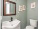 Cozy half bathroom with decorative botanical prints, wood-trimmed mirror, and sage green walls at 1420 E Market St, Indianapolis, IN 46201