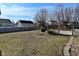 Open backyard showing deck, mature trees, and fenced perimeter, landscaped with lawn and some bushes at 1905 Windsor Ln, Danville, IN 46122