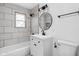 Stylish bathroom features a tub, tiled walls, and a modern vanity with a round mirror at 1912 Glenridge Dr, Indianapolis, IN 46218