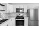 Modern kitchen with stainless steel appliances, white cabinets, and a contrasting black backsplash at 1912 Glenridge Dr, Indianapolis, IN 46218