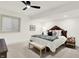 Bright bedroom with large bed, ceiling fan, neutral carpet, a sitting bench, and a side table at 19795 Chatham Shore Ln, Westfield, IN 46074