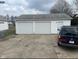 Two-car garage with white doors and a side entry door, situated on a concrete driveway at 2122 George St, Anderson, IN 46016