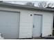 View of the garage's exterior with a white door and siding at 2122 George St, Anderson, IN 46016