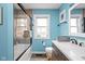 Stylish bathroom featuring a bathtub with glass doors, a vanity with modern fixtures, and bright blue walls at 2224 E Pleasant Run Parkway North Dr, Indianapolis, IN 46203
