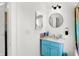 Updated bathroom with a blue vanity, two mirrors, and modern fixtures with storage on the side at 2401 N Olney St, Indianapolis, IN 46218