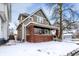 Charming two-story home featuring a welcoming front porch with brick accents and snow-covered yard at 2401 N Olney St, Indianapolis, IN 46218