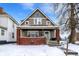 Charming two-story home featuring a welcoming front porch with brick accents and snow-covered yard at 2401 N Olney St, Indianapolis, IN 46218