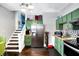 Cozy kitchen with green cabinets, stainless steel appliances, and stairs to another level at 2401 N Olney St, Indianapolis, IN 46218