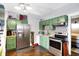 View of the kitchen featuring stainless steel appliances, green cabinetry, and wood flooring at 2401 N Olney St, Indianapolis, IN 46218