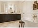 Elegant bathroom with stone floors, a stand-alone tub, and a double vanity with sconce lighting at 3588 Marketplace Ct, Zionsville, IN 46077