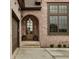 Arched front door with glass panes framed by brick and sconce lighting near the attached garage at 3588 Marketplace Ct, Zionsville, IN 46077