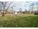 An open backyard showcases mature trees and neighborhood houses in the background at 7044 Bel Moore Cir, Indianapolis, IN 46259