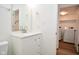 Bright bathroom boasts a white vanity with quartz countertop and a view to a laundry room with modern appliances at 7044 Bel Moore Cir, Indianapolis, IN 46259