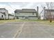 A rear view of the two-story home reveals green siding and a large concrete patio at 7044 Bel Moore Cir, Indianapolis, IN 46259