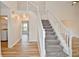 Bright foyer featuring a carpeted staircase with white railing and wood-look flooring throughout at 7044 Bel Moore Cir, Indianapolis, IN 46259