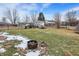 A firepit sits in the backyard on top of landscaping rocks, snow, and a patchy lawn at 803 Hickory Way, Noblesville, IN 46062