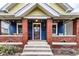 Inviting front porch with brick columns, blue siding, decorative lighting, and a cozy seating area at 85 N Dearborn St, Indianapolis, IN 46201