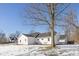 View of the back of a white house with dark roof surrounded by a snowy yard on a bright, clear day at 10539 Mcpherson St, Carmel, IN 46280