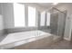 Bright bathroom showing a bathtub, a glass shower, neutral colored tiling, and large windows at 15694 Provincial Ln, Fishers, IN 46040